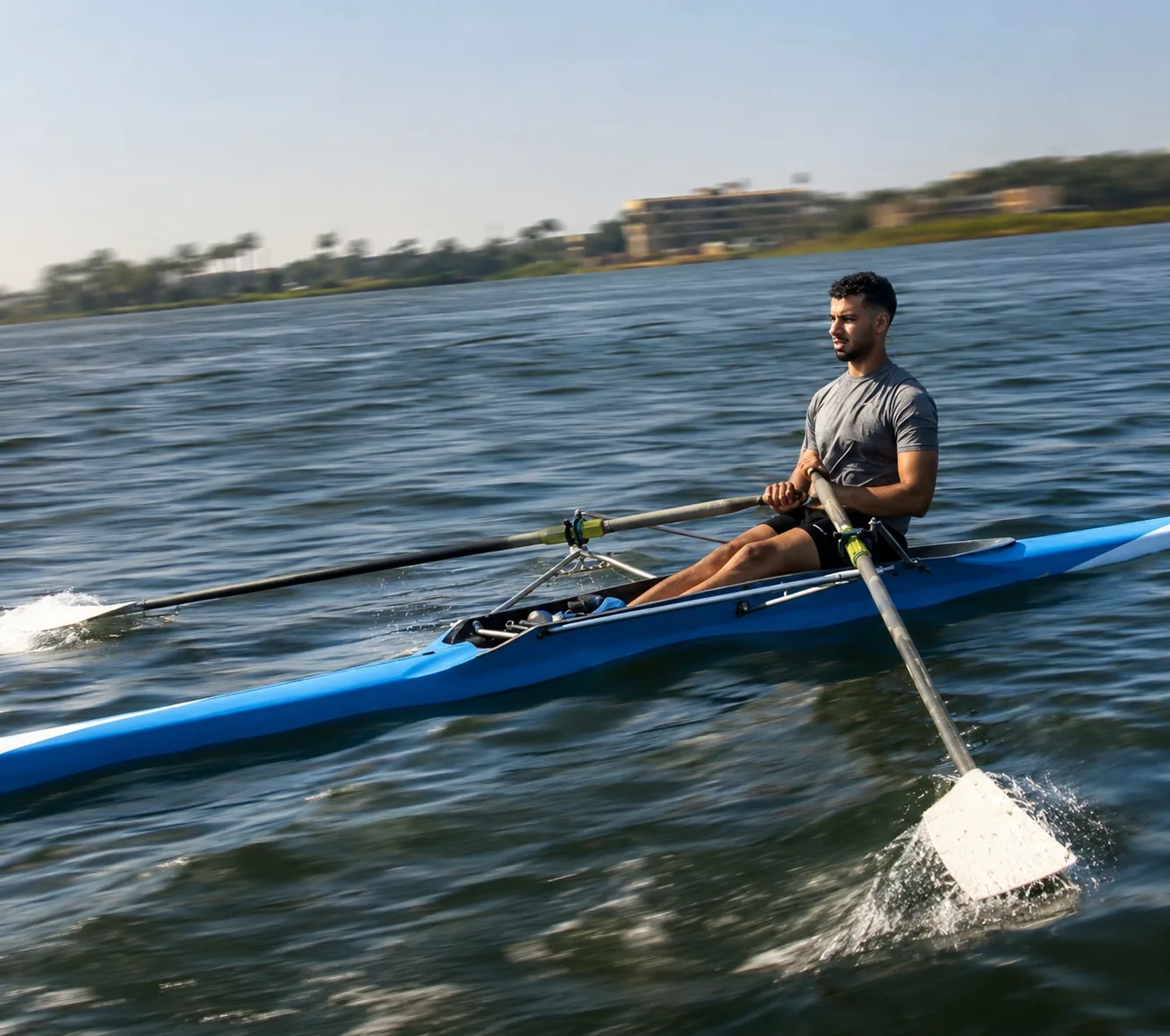 Rowing a single scull on flat water, mid-stroke.